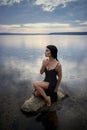 Beauty brunette woman in a black dress poses in a sea lake against a blue sky background. Long hair sexy woman and beautiful Royalty Free Stock Photo