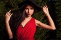Beauty brunette women in red dress & hat pose at night park. Royalty Free Stock Photo