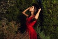 Beauty brunette women in red dress & hat pose at night park. Royalty Free Stock Photo