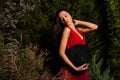 Beauty brunette women in red dress & hat pose at night park. Royalty Free Stock Photo