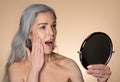 Beauty care. Shocked senior woman looking in magnifying mirror with open mouth, enjoying new treatment Royalty Free Stock Photo