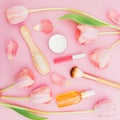 Beauty composition with tulips flowers and makeup feminine cosmetic, aroma and comb on pink background. Top view. Flat lay.