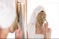 Beauty concept. The woman applies green organic face mask in the bathroom