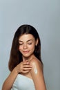Beauty Concept. Woman holds a cosmetic crem in her hand and spreads it on her shoulder  to moisturize her skin. Royalty Free Stock Photo