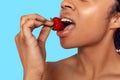 Beauty Concept. Young african woman isolated on blue biting strawberry sensual close-up Royalty Free Stock Photo