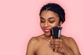 Beauty Concept. Young african woman wearing makeup isolated on pink with brushes looking down shy Royalty Free Stock Photo