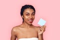 Beauty Concept. Young african woman wearing makeup isolated on pink holding sticker explaining information smiling Royalty Free Stock Photo