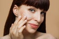 Beauty cosmetics. Close up beautiful red hair woman applying tonal cream base on face.