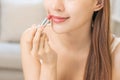 Beauty cosmetics concept, hand of asian young woman, girl make up face by applying lipstick, lips balm on her mouth, looking at Royalty Free Stock Photo