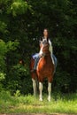 Beauty cowgirl riding painted horse down the path in the evening