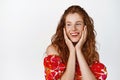 Beauty. Cute smiling redhead woman in summer floral dress, gazing flirty aside and grinning, standing happy against