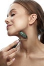 Beauty face care. Woman doing face massage with jade facial rollers for spa skin care treatment