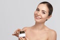 Beauty face model. Beautiful Woman with healthy smooth facial clean skin holding bottle cosmetic cream Royalty Free Stock Photo