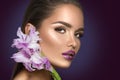 Beauty fashion brunette girl with gladiolus flowers. Glamour woman with perfect violet trendy makeup Royalty Free Stock Photo