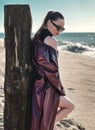 Beauty Fashion brunette model girl wearing stylish coat and sunglasses, posing on seaside Royalty Free Stock Photo