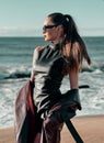 Beauty Fashion brunette model girl wearing stylish coat and sunglasses, posing on seaside Royalty Free Stock Photo