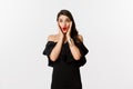 Beauty and fashion concept. Attractive woman in glamour black dress, jewelry and makeup, looking surprised and excited