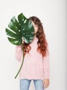 Beauty and fashion concept: Little curly girl child holding big green leaf. Isolated over white background. Royalty Free Stock Photo