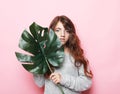 Beauty and fashion concept: Little curly girl child holding big green leaf.  over pink background. Royalty Free Stock Photo