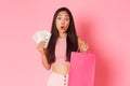 Beauty, fashion and lifestyle concept. Beautiful amazed asian woman in trendy clothes, holding shopping bags and money