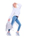 Beauty fashion model girl dressed in jeans and sneakers, holding trendy silver backpack and posing in studio