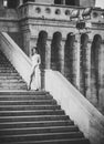 Beauty Fashion model girl. Fashion look. Young woman in white long dress stepping up staircase Royalty Free Stock Photo