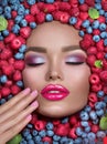 Beauty fashion model girl lying in fresh ripe fruits, berries and mint. Face in colorful berries close-up. Beautiful make-up Royalty Free Stock Photo