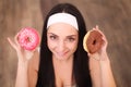 Beauty fashion model girl taking sweets and colorful donuts. Funny joyful styled woman with sweets on wood background. Diet, dieti Royalty Free Stock Photo