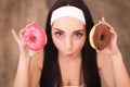 Beauty fashion model girl taking sweets and colorful donuts. Funny joyful styled woman with sweets on wood background. Diet, dieti Royalty Free Stock Photo