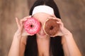 Beauty fashion model girl taking sweets and colorful donuts. Funny joyful styled woman with sweets on wood background. Diet, dieti Royalty Free Stock Photo