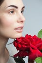 Beauty Fashion Model Woman face. Portrait with Red Rose flowers. Perfect skin. Royalty Free Stock Photo