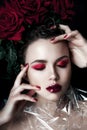 Beauty Fashion Model Woman face. Portrait with Red Rose flowers. Red Lips and Nails. Beautiful Brunette Woman with Luxury Makeup, Royalty Free Stock Photo