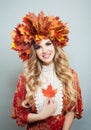 Beauty fashion portrait of pretty autumn woman in bright fall leaves crown with red maple leaf