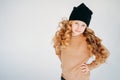 Beauty fashion portrait of smiling curly hair tween girl in black hat and beige sweater on the white background Royalty Free Stock Photo