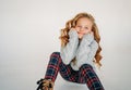 Beauty fashion portrait of smiling curly hair tween girl in cozy knitted sweater and plaid pants on white background isolated Royalty Free Stock Photo