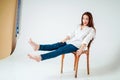 Beauty fashion portrait of smiling sensual asian young woman with dark long hair in white shirt sitting on chair on white Royalty Free Stock Photo
