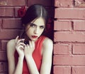 Beauty and fashion, spanish woman with fashionable makeup and rose flower in hair, girl in red dress on brick wall Royalty Free Stock Photo