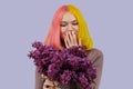 Surprised teenager girl with dyed pink yellow hair holding lilac flowers in hands Royalty Free Stock Photo