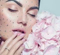 Beauty fashion Woman face decorated with gem stones, crystals. Closeup Portrait with Hydrangea. Model girl with holiday makeup