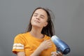 Beauty and fashion. A young Caucasian woman dries her hair with a hairdryer on a gray background Royalty Free Stock Photo