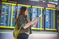 Beauty female tourist looking at flight schedules for checking t Royalty Free Stock Photo