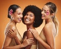 Beauty, flowers and women in makeup, diversity and models on orange studio background. Smile, skincare and happy, young