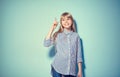 Beauty funny blonde teenage girl has an idea, pointing finger, showing empty copy space for text, blue background