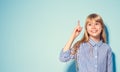 Beauty funny blonde teenage girl has an idea, pointing finger, showing empty copy space for text, blue background