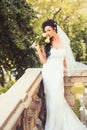 Beauty girl with bridal makeup and hairstyle. Sensual woman with wedding bouquet. Woman with flowers on balcony. Bride