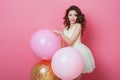 Beauty girl with colorful air balloons laughing over pink background. Beautiful Happy Young woman on birthday holiday party. Fashi Royalty Free Stock Photo