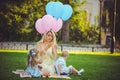 Beauty girl with colorful balloons laughing with two children. Beautiful happy young woman on a walk in the park. pastel colors Royalty Free Stock Photo