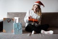Beauty girl opening present gifts sitting on sofa at home Royalty Free Stock Photo