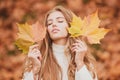 Beauty girl outdoors enjoying nature. Beautiful autumn female model holds an yellow leaf near the face. Fashion portrait Royalty Free Stock Photo