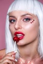 Beauty Glamour model woman with trendy white hair style and creative makeup holding red sweet lollipop candy Royalty Free Stock Photo